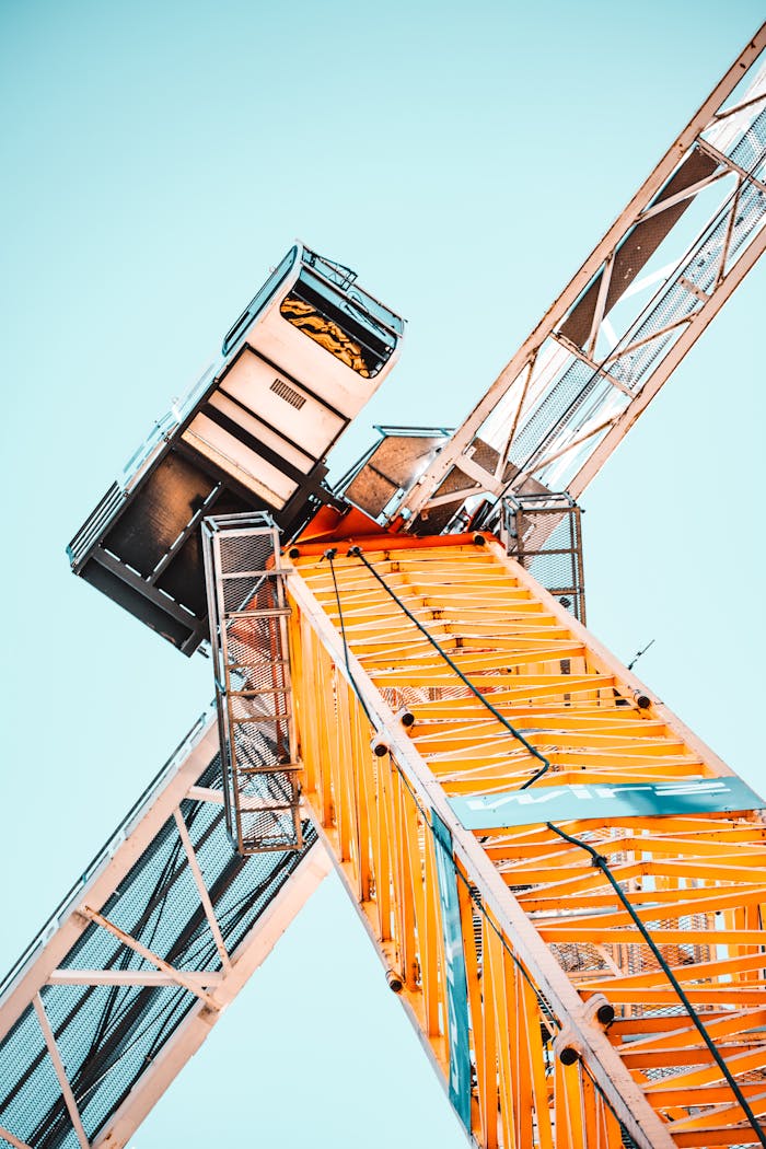 embark A striking low angle shot of a vibrant yellow tower crane against a clear sky, showcasing industrial power.
