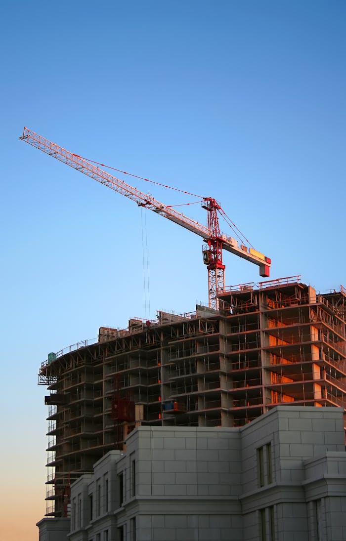 services-03 Tower crane on a high-rise building under construction at sunset, showcasing modern urban development.